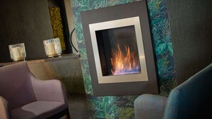 Una habitación moderna con chimenea, papel tapiz estampado y una zona de estar con una silla.