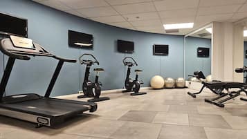 A gym with treadmills, elliptical machines, and exercise balls.