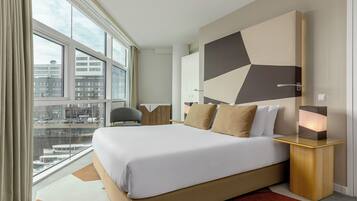 Ein modernes Hotelzimmer mit großem Bett, Blick auf die Stadt und einem geometrischen Wanddesign.