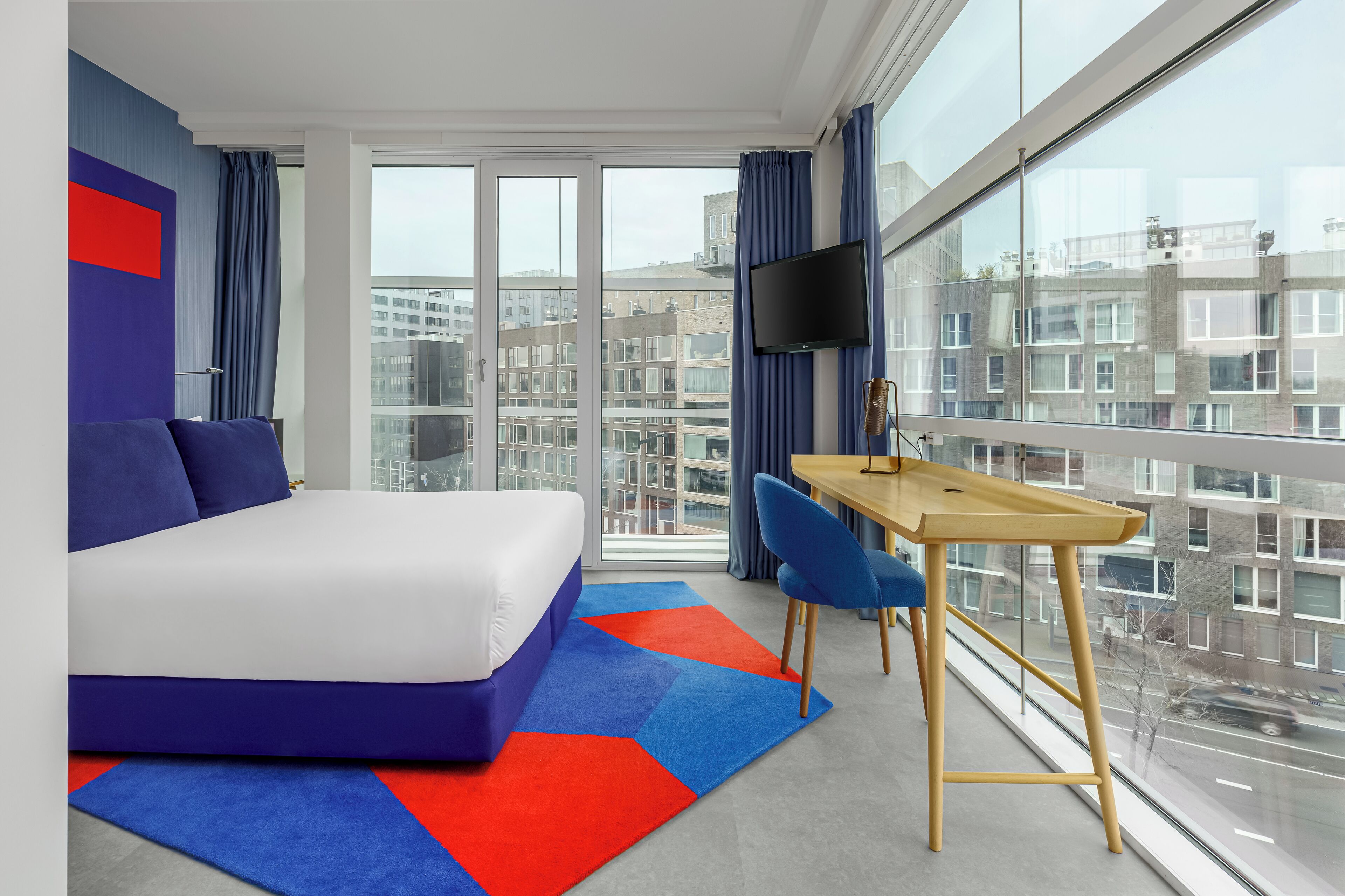 Een moderne hotelkamer met een groot bed, een bureau en een televisie.