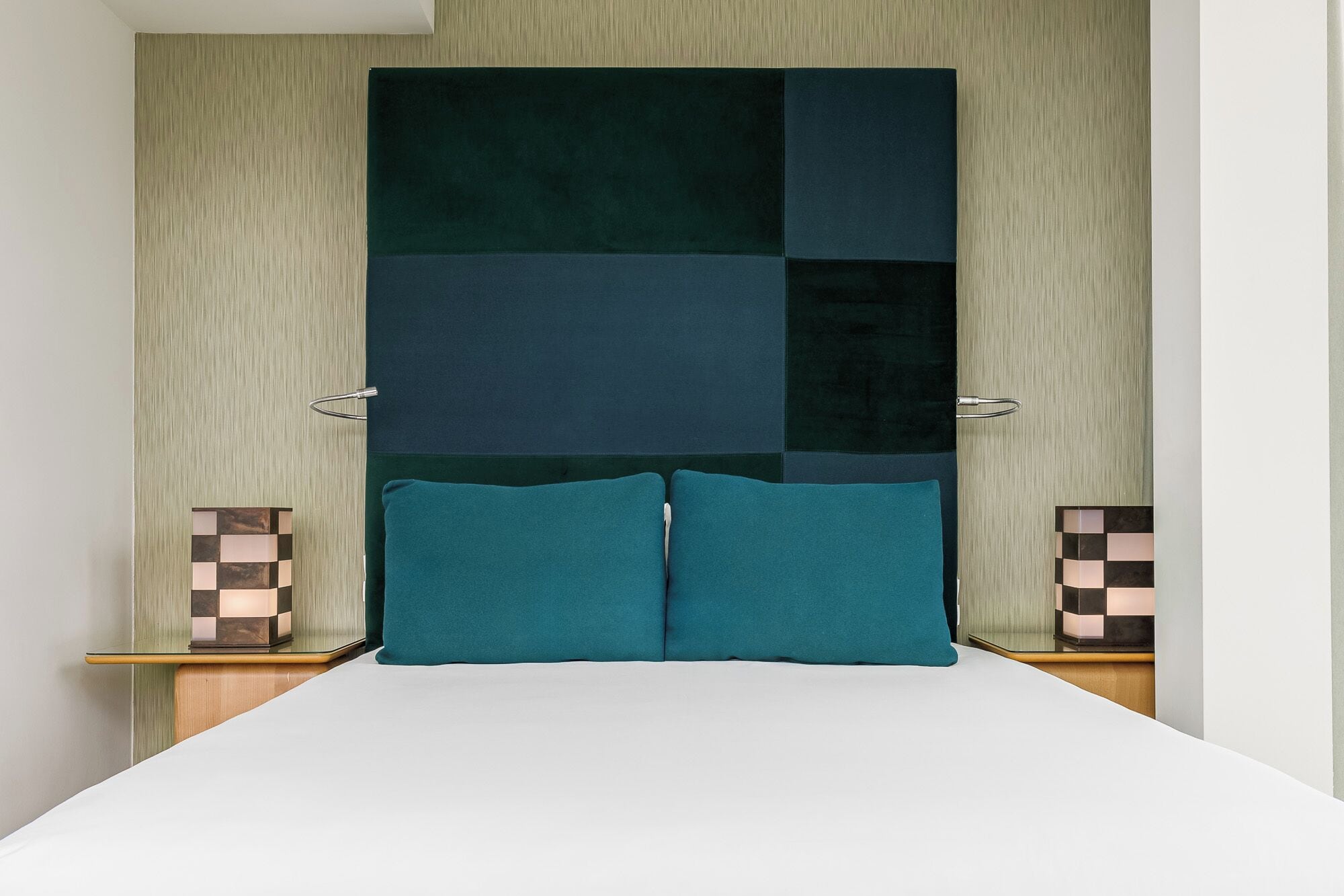 Un dormitorio con una cama grande, dos mesitas de noche y una pared con diseño geométrico.