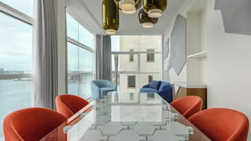 Ein moderner Konferenzraum mit einem Glastisch, roten und blauen Stühlen und großen Fenstern mit Blick auf eine Skyline.