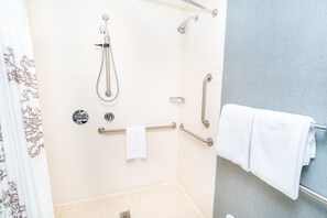 A shower area with a grab bar, a towel rack, and a showerhead.