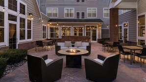 Un espace patio aménagé avec du mobilier d’extérieur, un foyer et des guirlandes lumineuses.