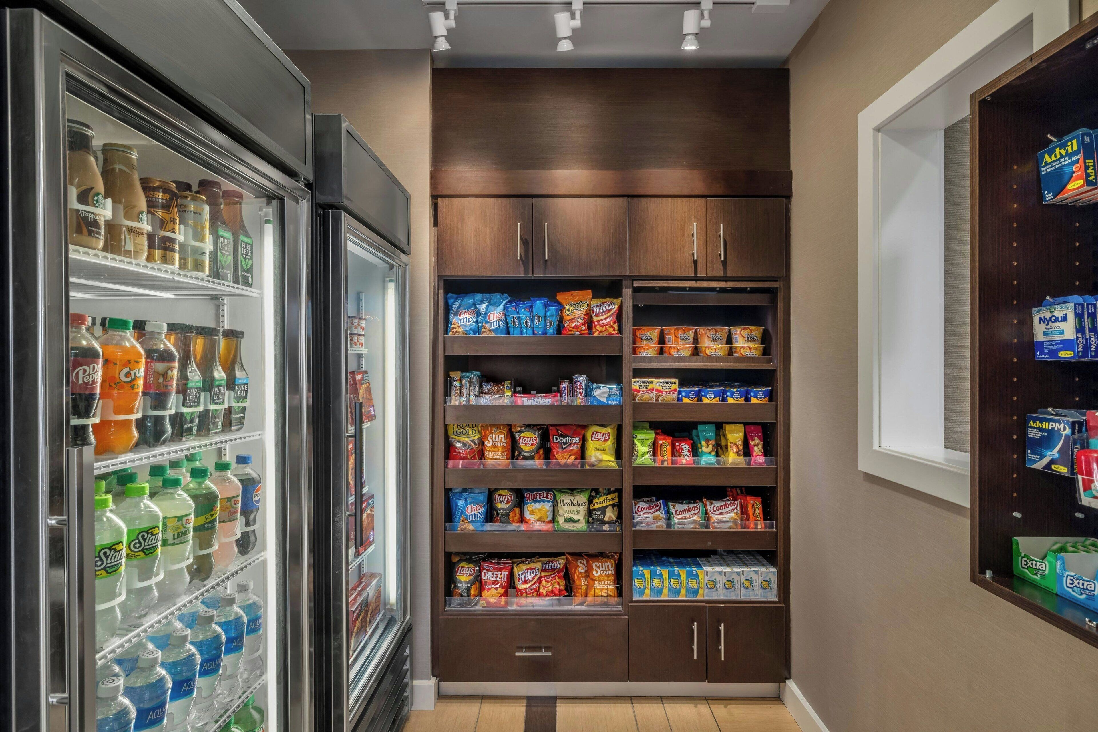 A refrigerated beverage cooler stocked with various drinks and a pantry stocked with snacks and personal care items.