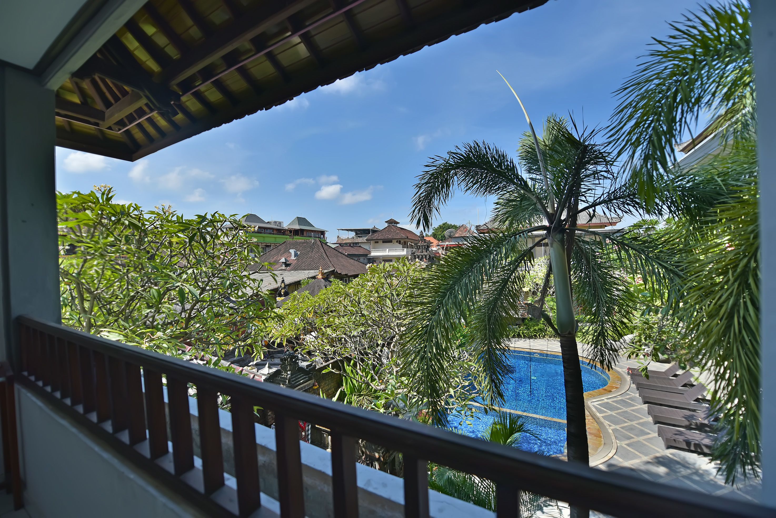 A view of a swimming pool surrounded by palm trees and houses.