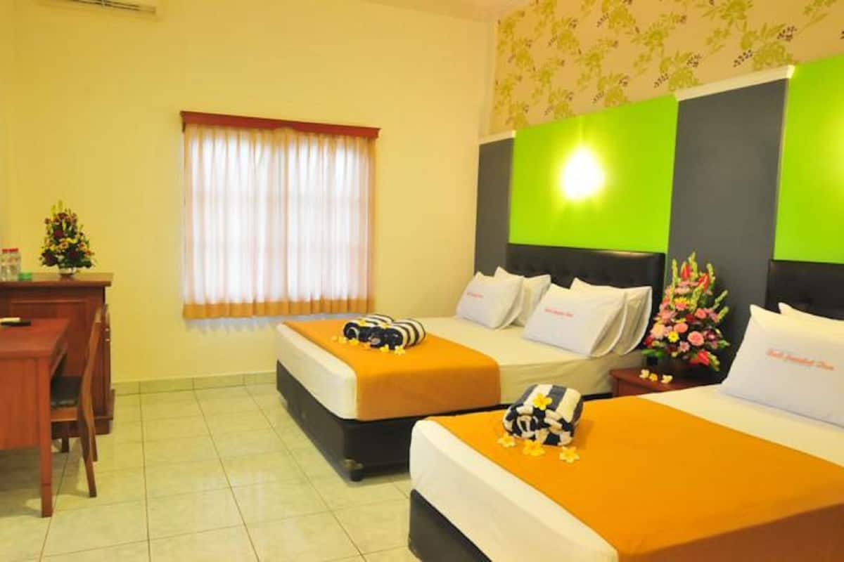 A hotel room with two beds, a desk, a television, and a window with curtains.