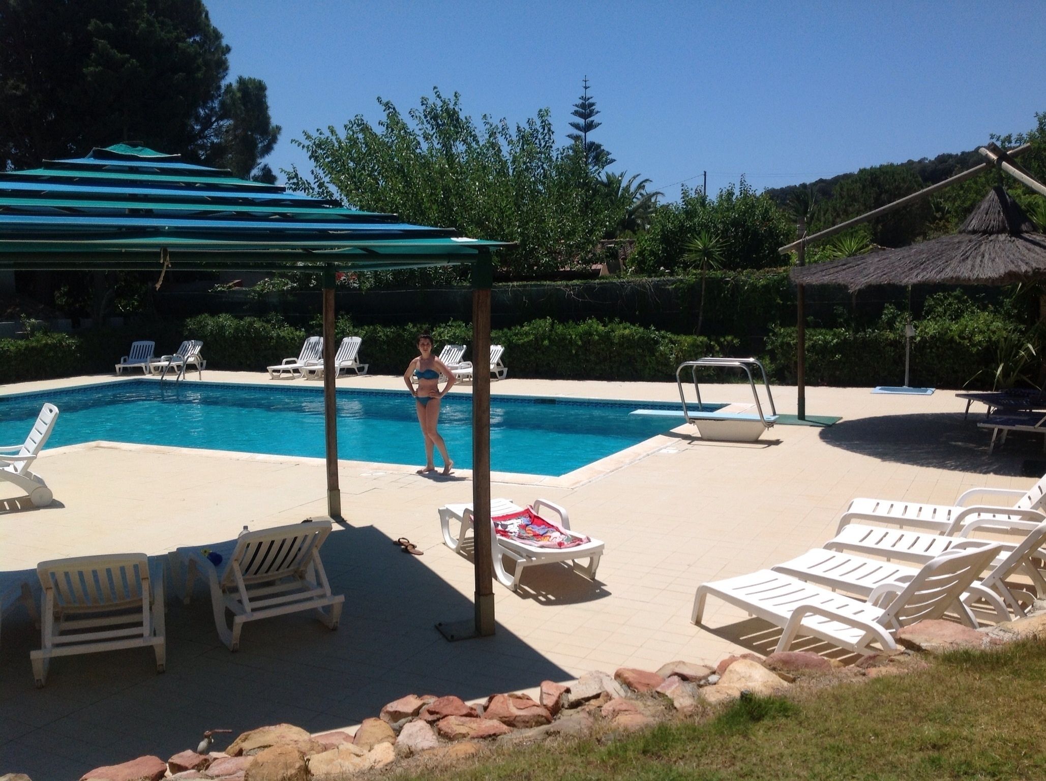 Uma área de piscina com espreguiçadeiras, um espaço coberto para sentar e uma piscina pequena.