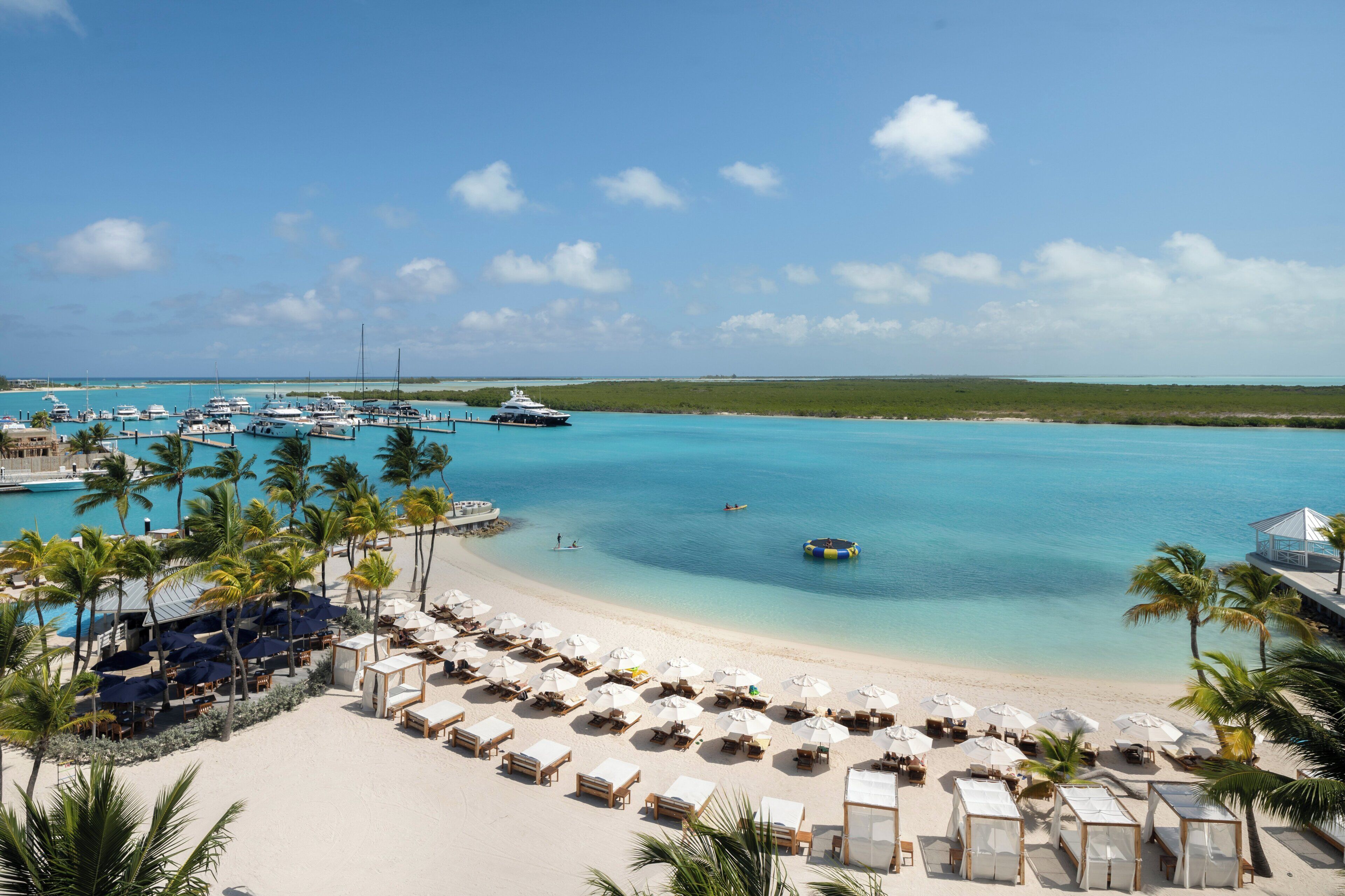 A beach resort with a marina, sun loungers, umbrellas, and a clear view of the ocean.