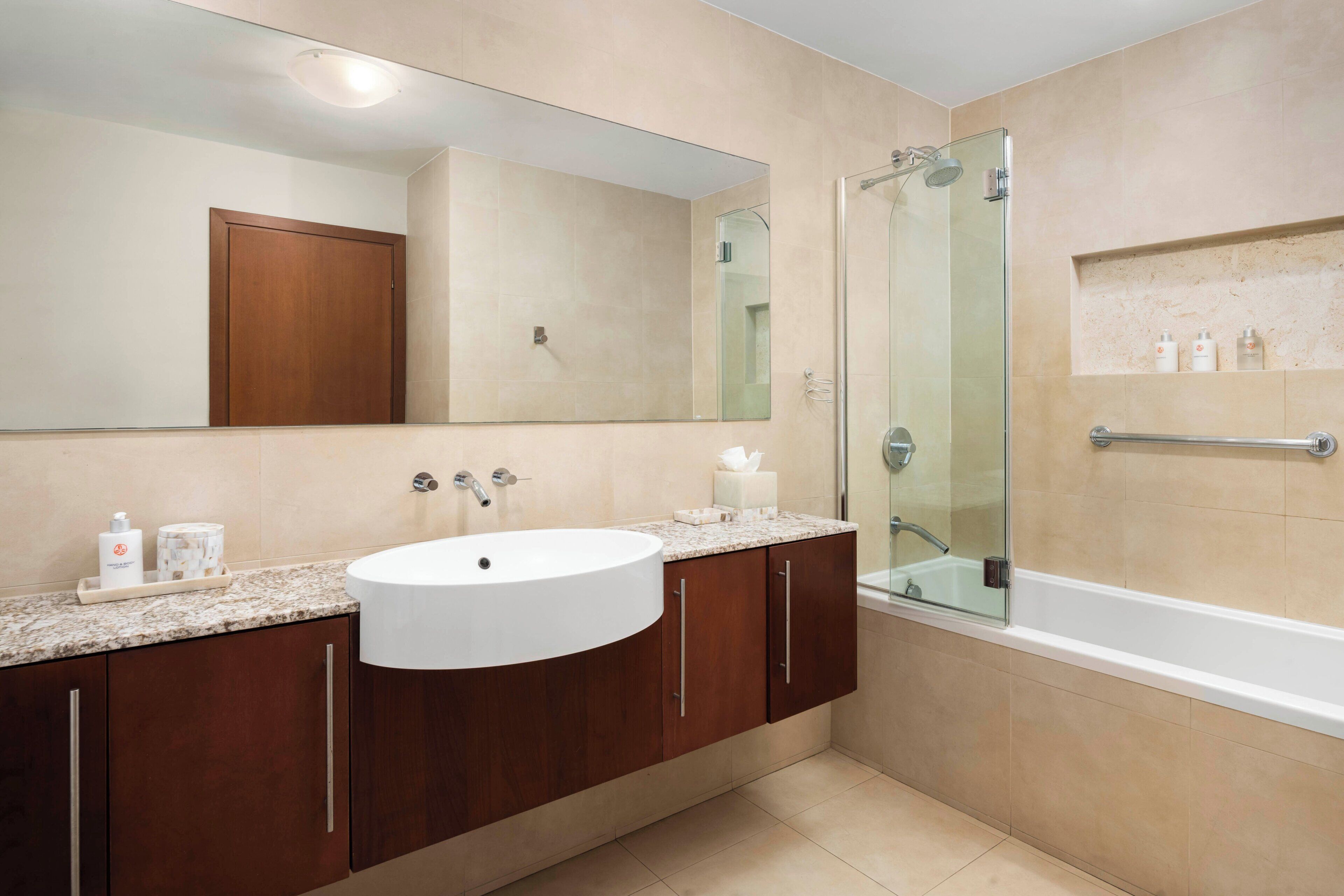 A bathroom with a large mirror, a sink, a shower, and a bathtub.