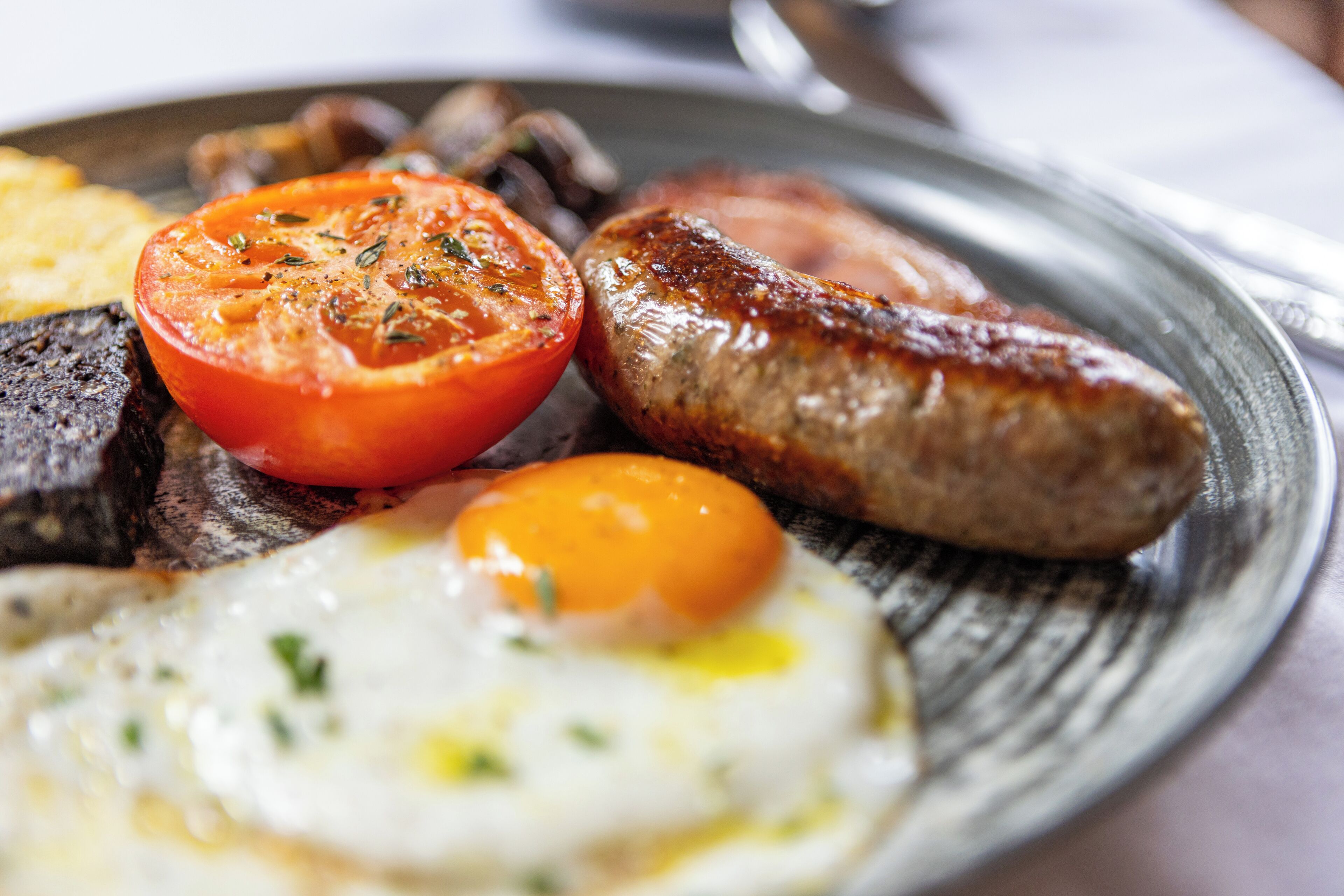 A breakfast plate with eggs, sausages, tomatoes, and mushrooms.