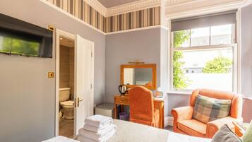 Ein Hotelzimmer mit Bett, Schreibtisch, Stuhl, Fernseher und Fenster.