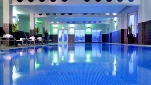Una amplia piscina interior con suelo de azulejos azules y diseño moderno.