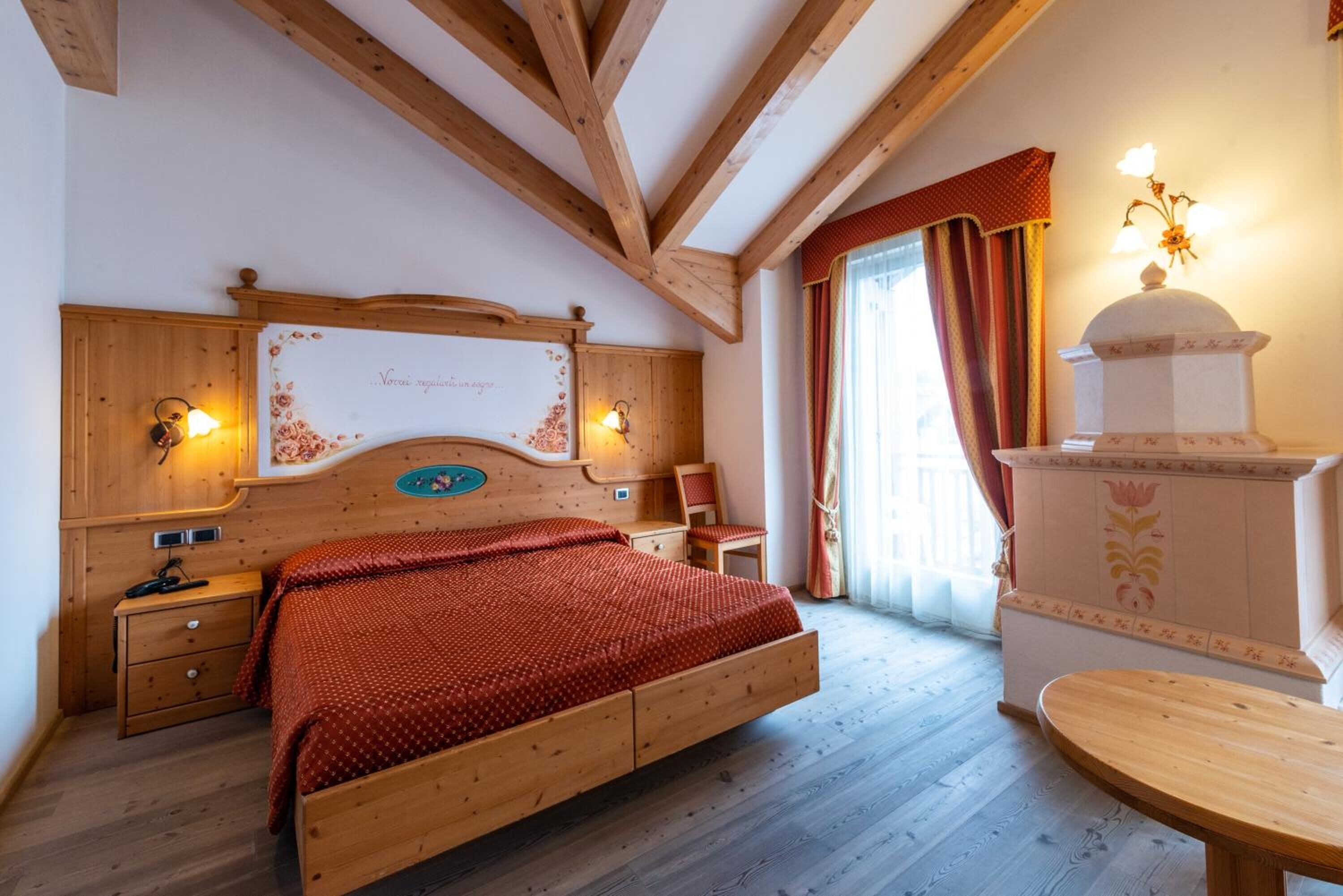 A wooden-framed bedroom with a bed, bedside tables, and a decorative wall piece.