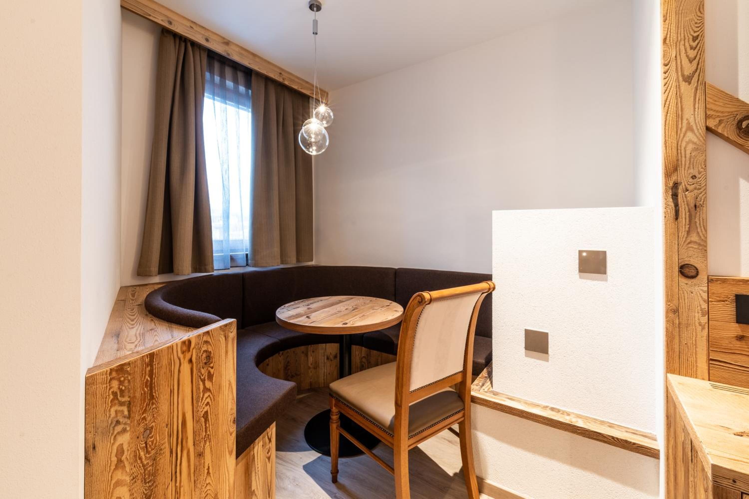 Un coin salon accueillant avec un banc incurvé, une table ronde en bois et une chaise.