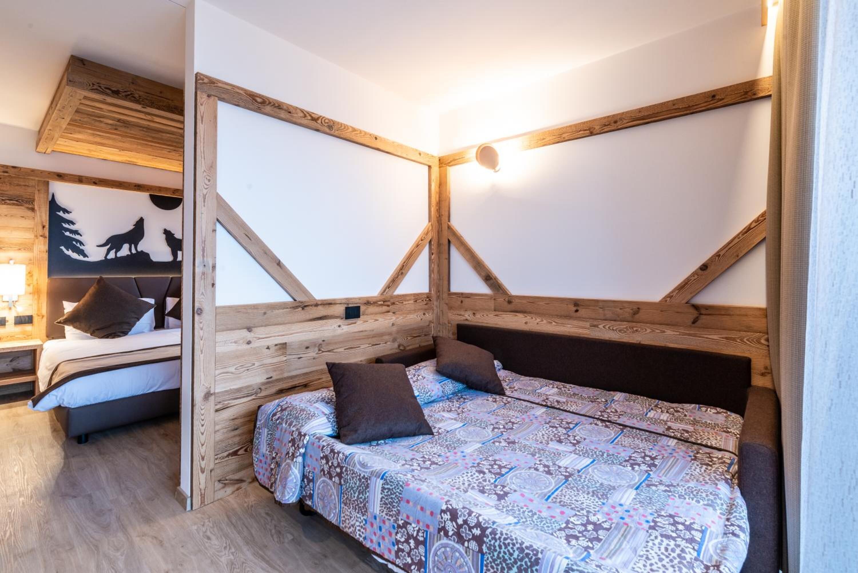 A cozy bedroom with a wooden ceiling, a patterned bedspread, and a wall-mounted light fixture.