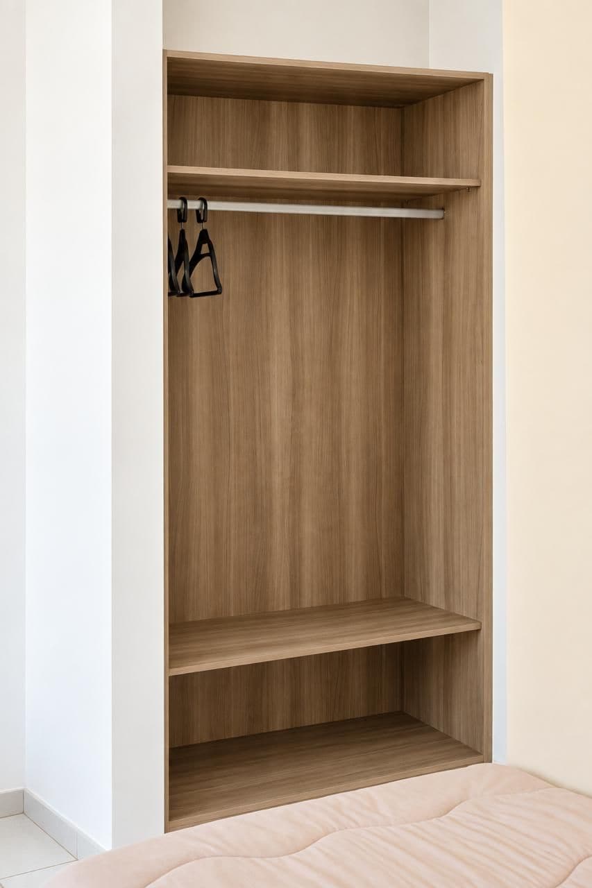 A walk-in closet with wooden shelving and a hanging rod.