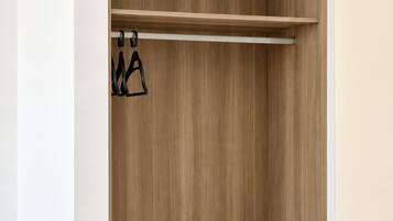 A walk-in closet with wooden shelving and a hanging rod.