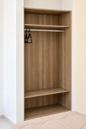Un armario con estantes de madera y barra para colgar.