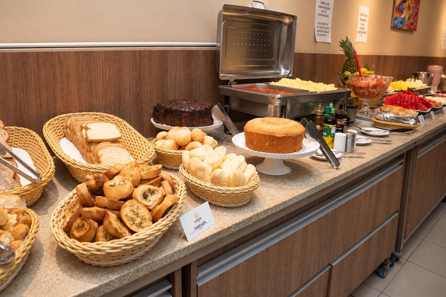 Buffet com diversos alimentos, incluindo pão, doces e um bolo.