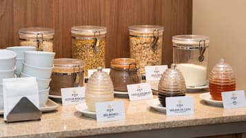 A buffet counter with various food items in glass containers, each labeled with the name of the dish.