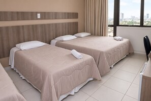 A hotel room with two beds, a desk, and a window with a city view. - Getúllio Hotel (Cuiabá)