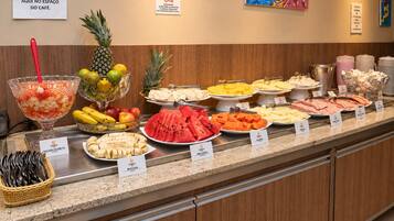 A buffet with various fruits and dishes labeled with their names.