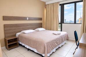 Een hotelkamer met een groot bed, een bureau en uitzicht op de stad.