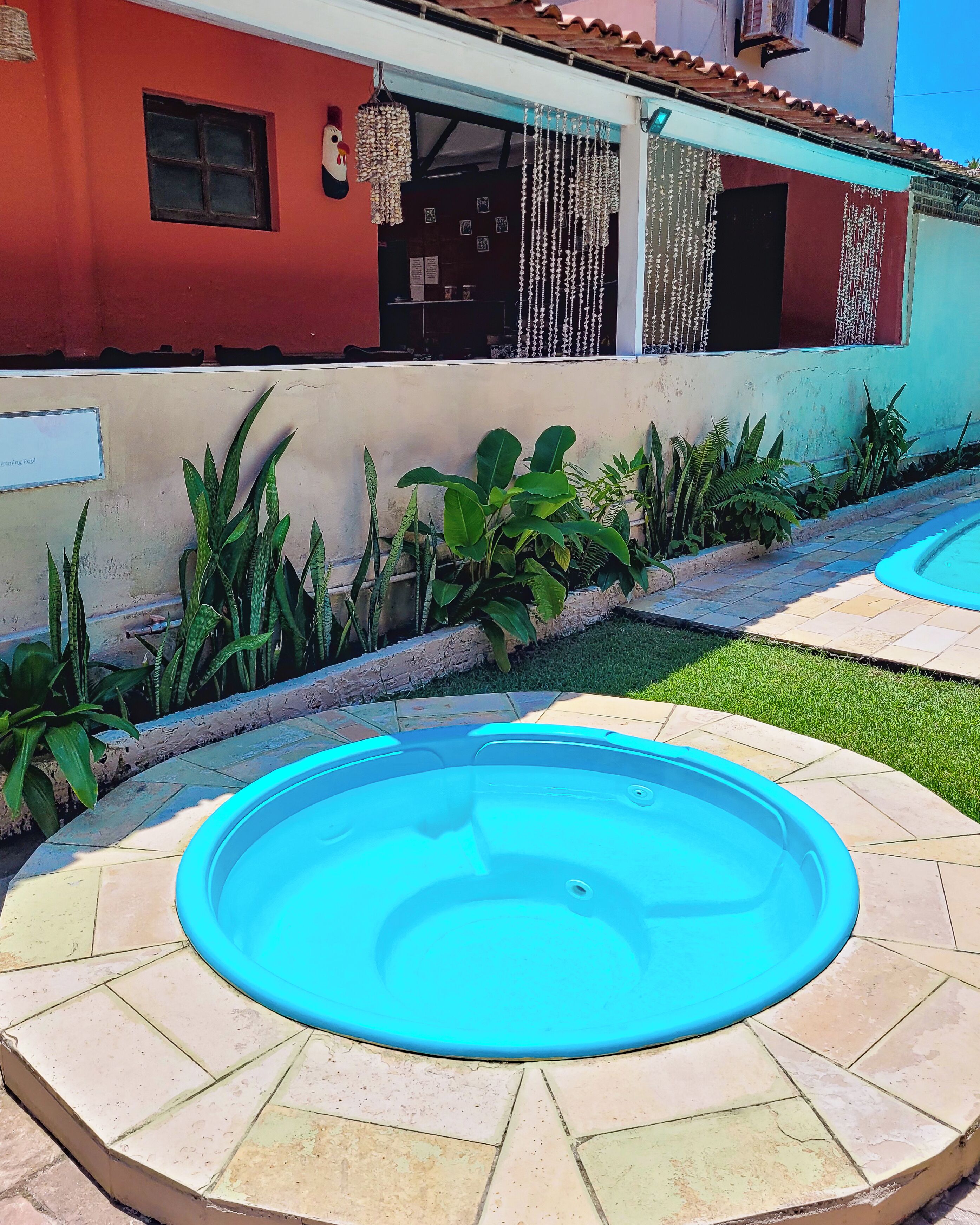 Zona de piscina con suelo de baldosas y un edificio al fondo.