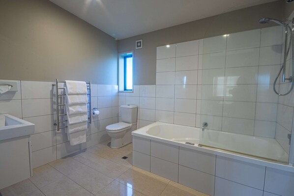 A modern bathroom with a toilet, sink, and bathtub. - Amity Court Motel (Stratford)