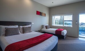 A hotel room with two beds, a window with blinds, and a red artwork on the wall. - Amity Court Motel (Stratford)