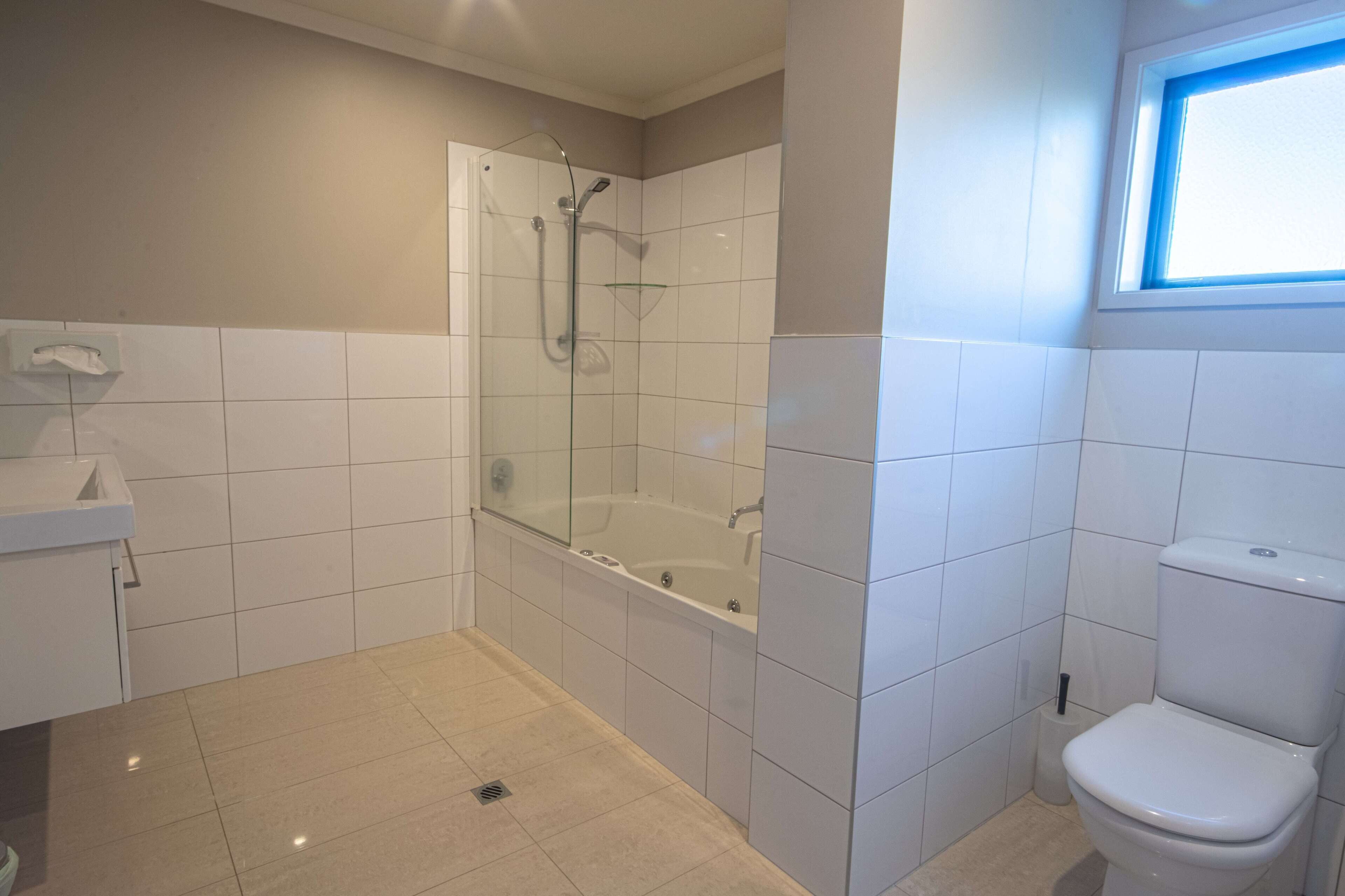 A bathroom with a glass-enclosed shower, a bathtub, and a toilet.