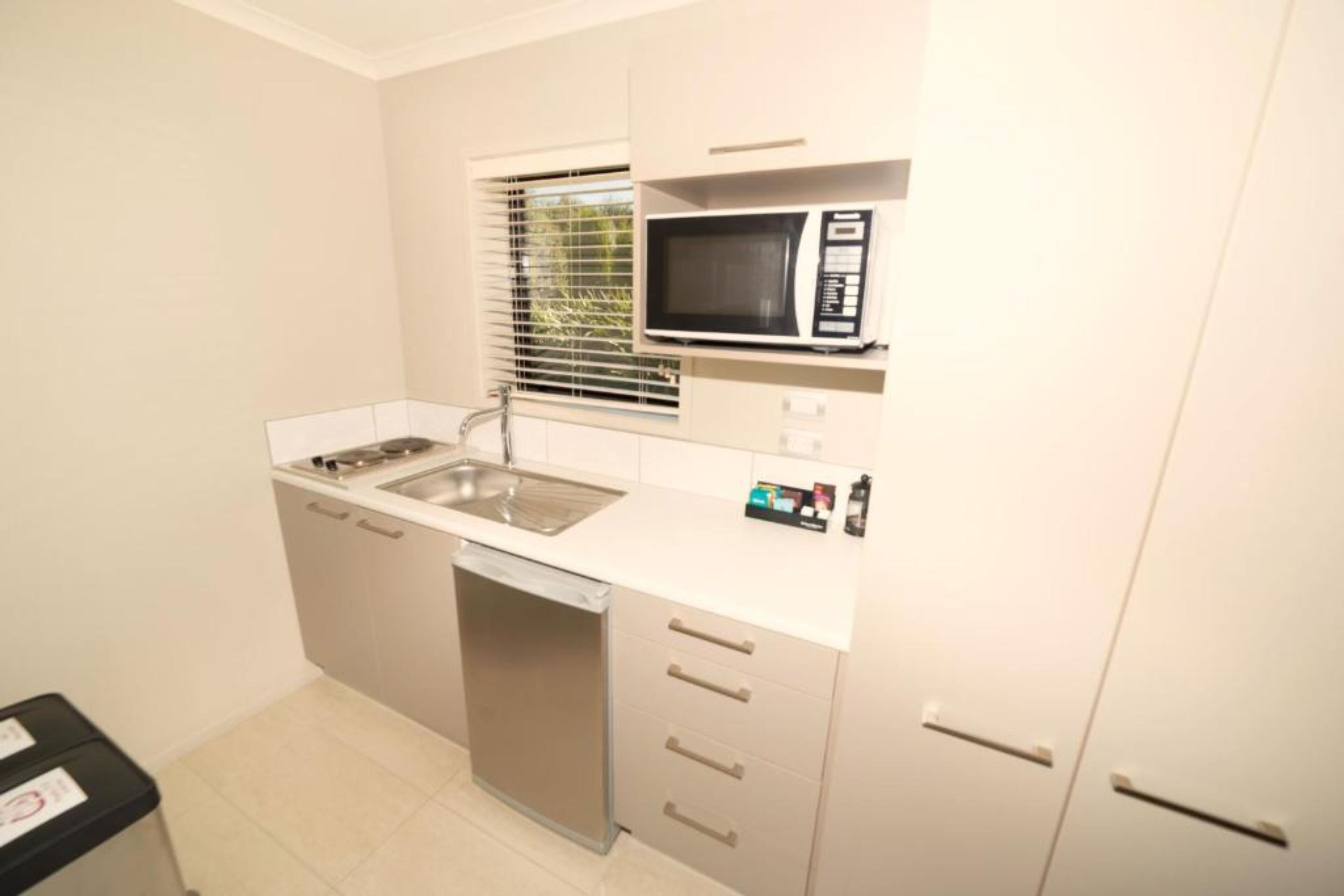 Una cocina compacta equipada con microondas, lavavajillas y fregadero.