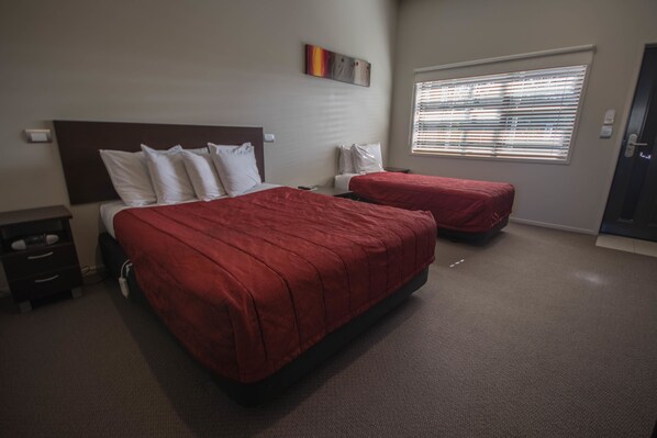 A hotel room with two beds, a nightstand, a dresser, and a window with blinds. - Amity Court Motel (Stratford)