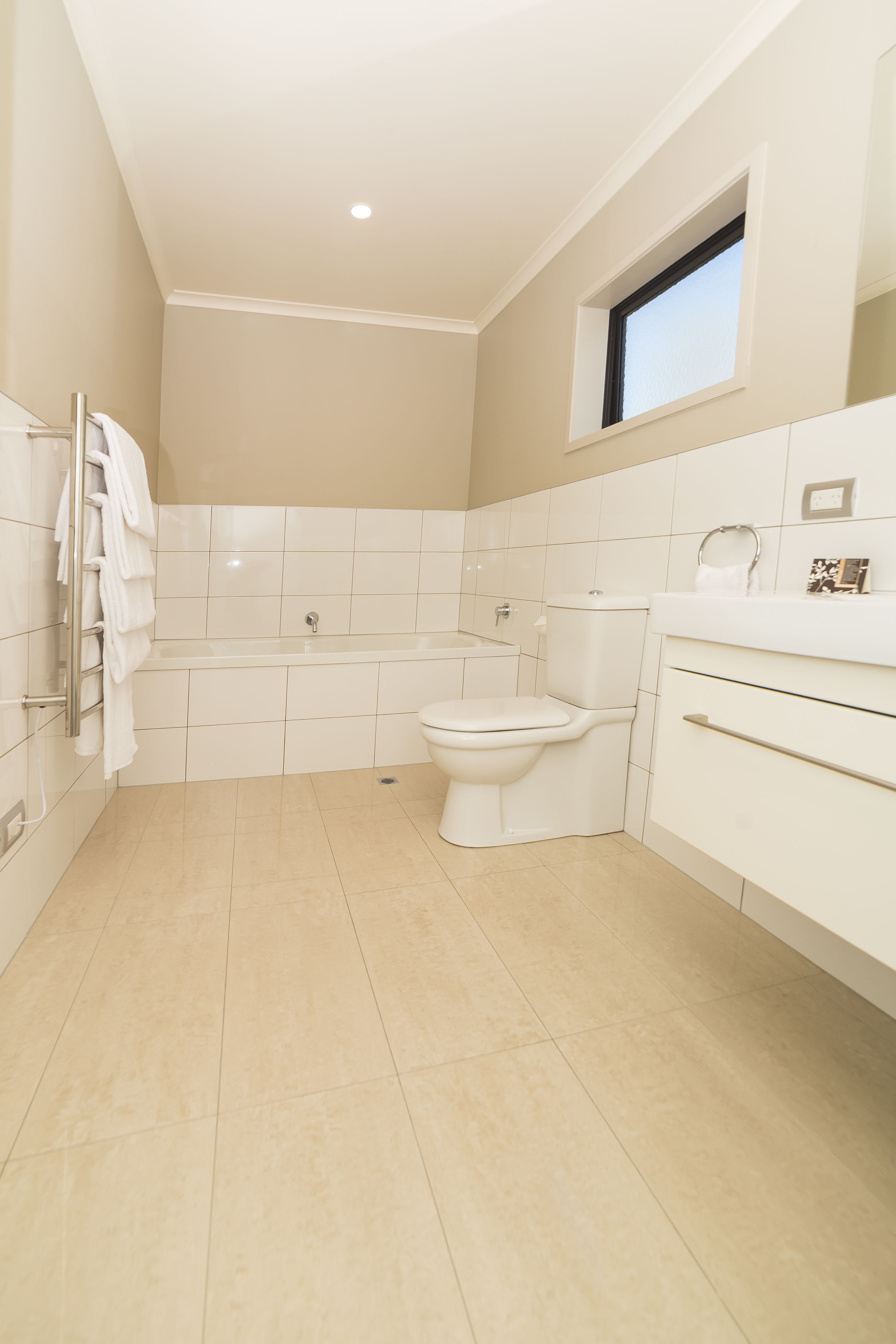 A modern bathroom with a bathtub, toilet, and vanity.