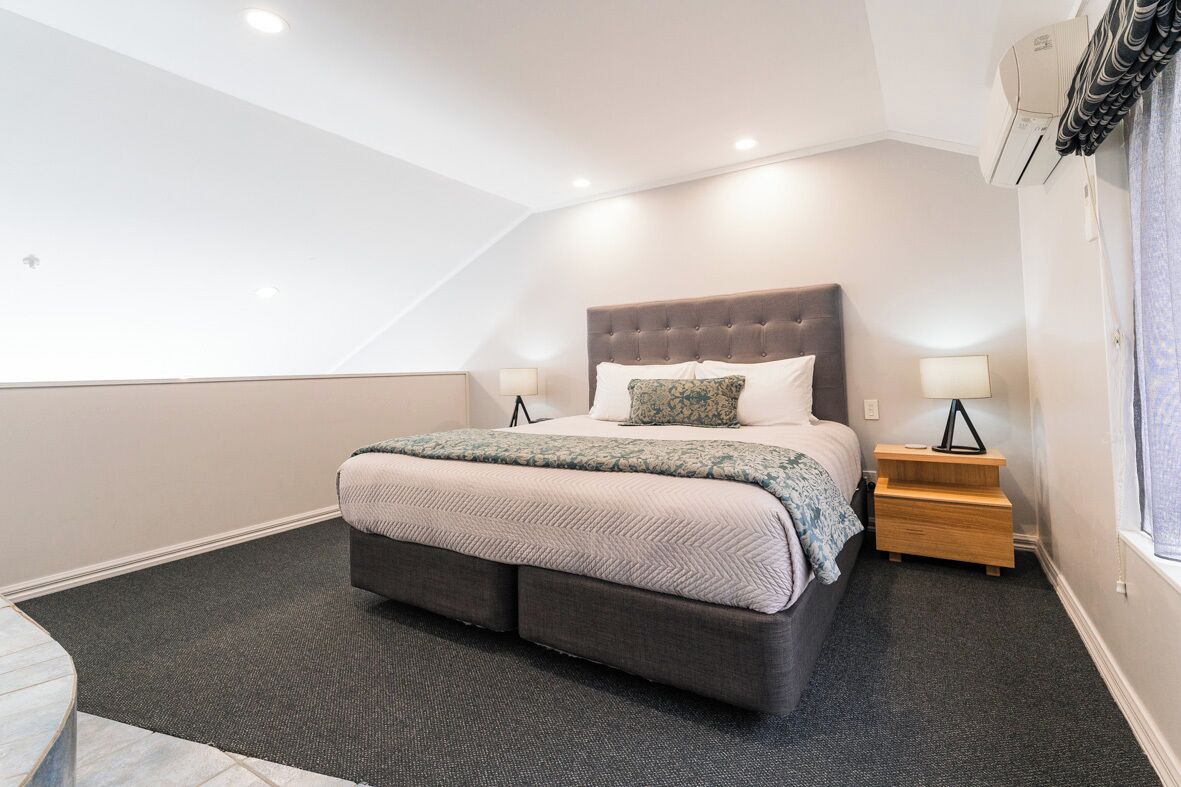 A modern bedroom with a large bed, two bedside tables, and a ceiling fan.