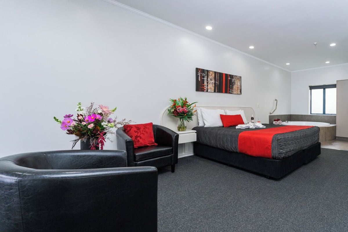 A modern hotel room with a large bed, a sofa, a desk, and a bathroom.