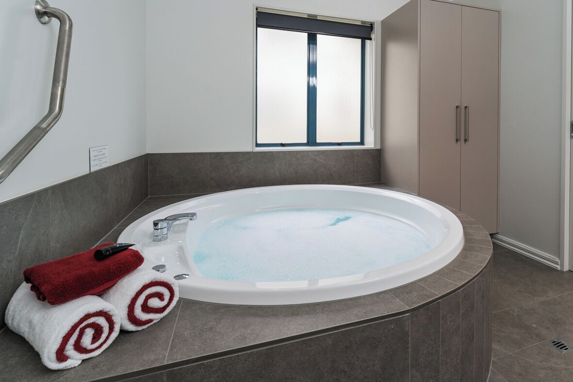A modern bathroom with a freestanding bathtub, a window, and a towel rack with red and white towels.