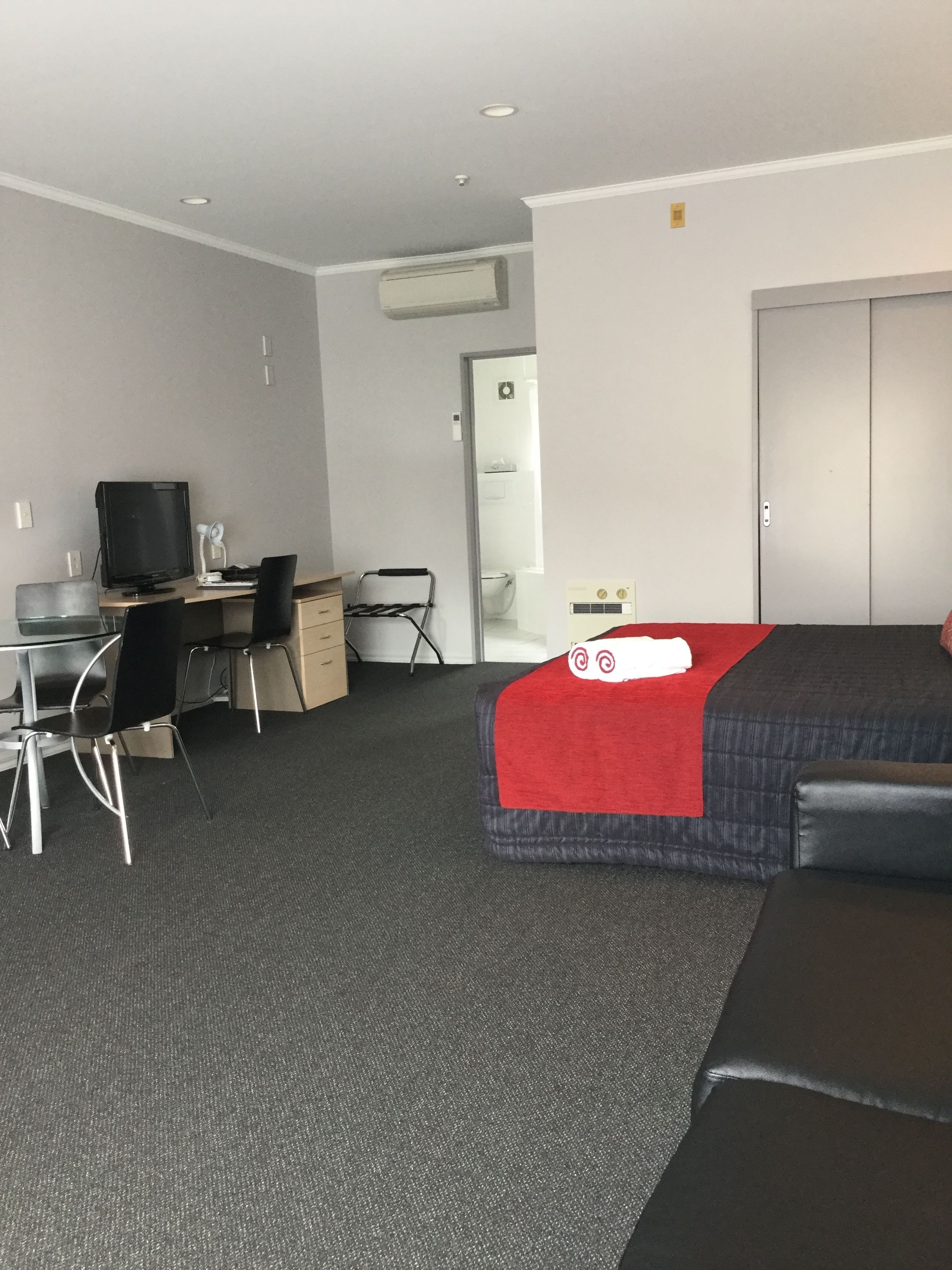 A hotel room with a bed, a desk with a computer, a chair, and a television.