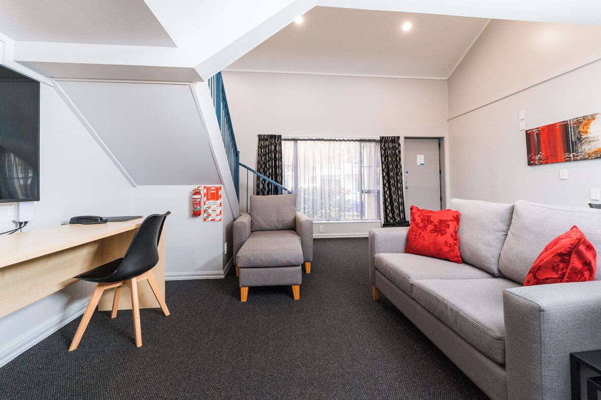 Una sala de estar moderna con un escritorio, un sofá gris y un sillón.