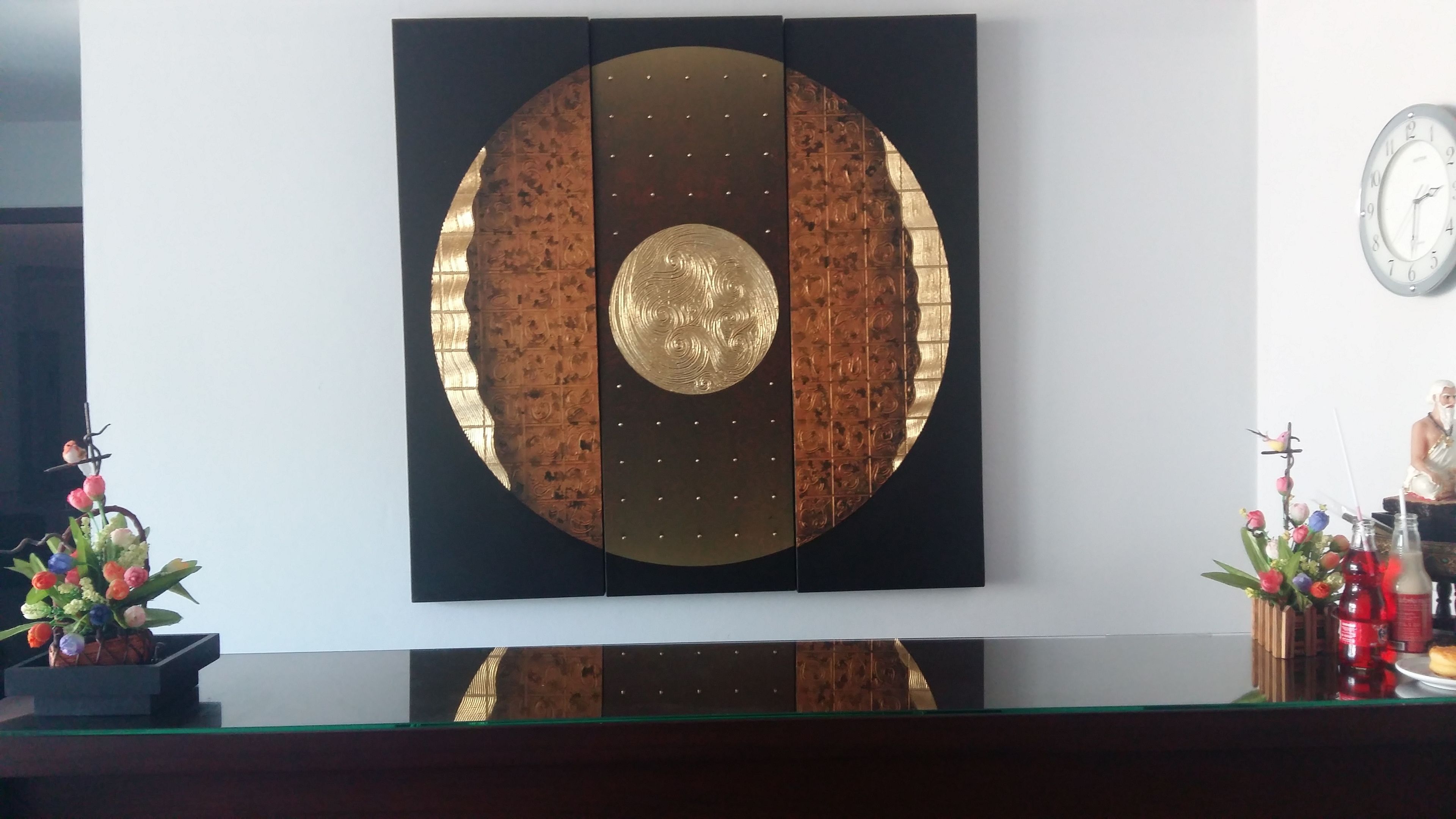 A wall-mounted decorative panel with a circular design and a clock on the wall.