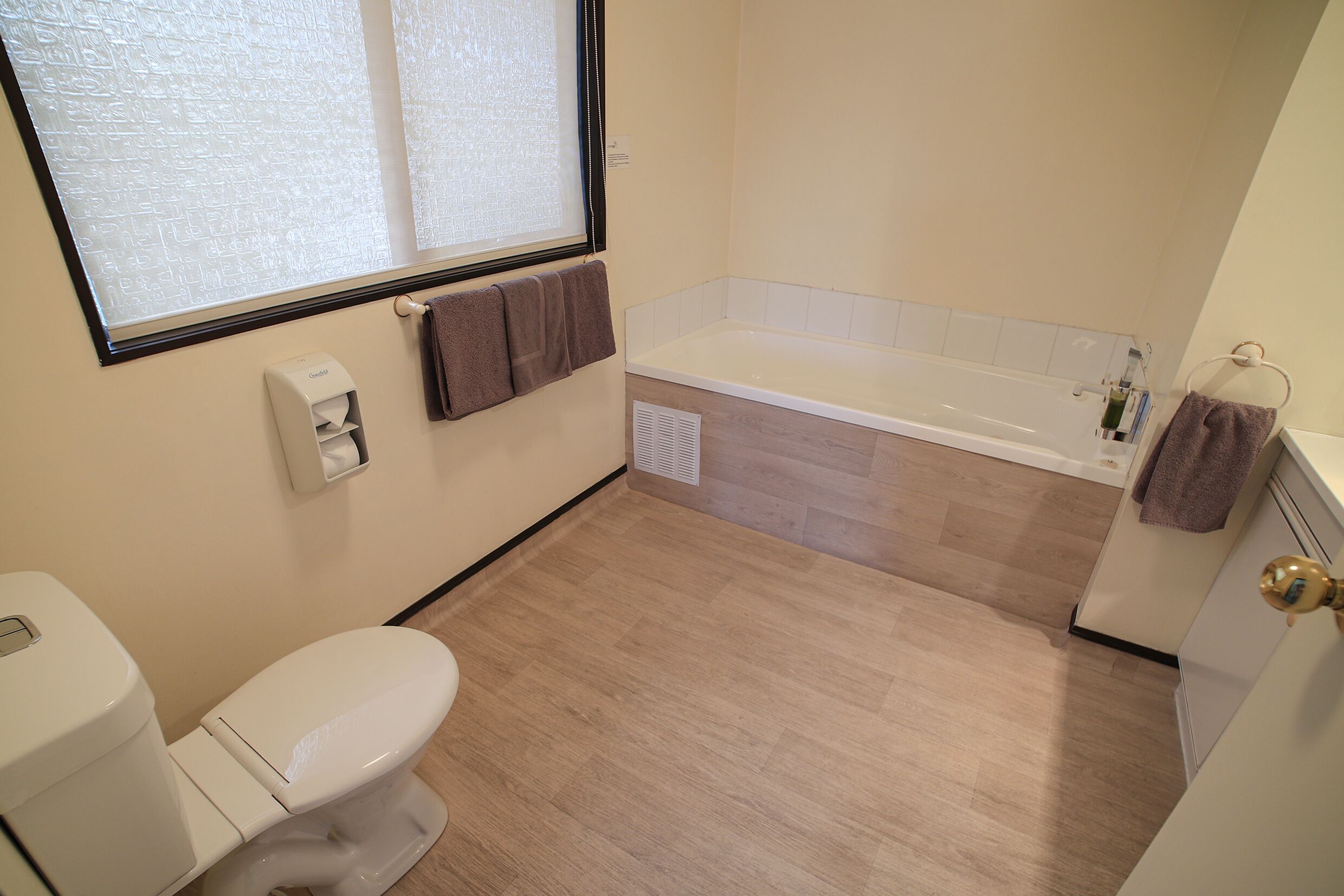 A bathroom with a toilet, a bathtub, and a window.