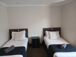Habitación doble con dos camas individuales, cada una con una almohada y una toalla enrollada.