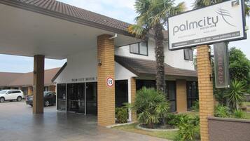 Hotel Palm City Motor Inn con un letrero que muestra piscina y spa.