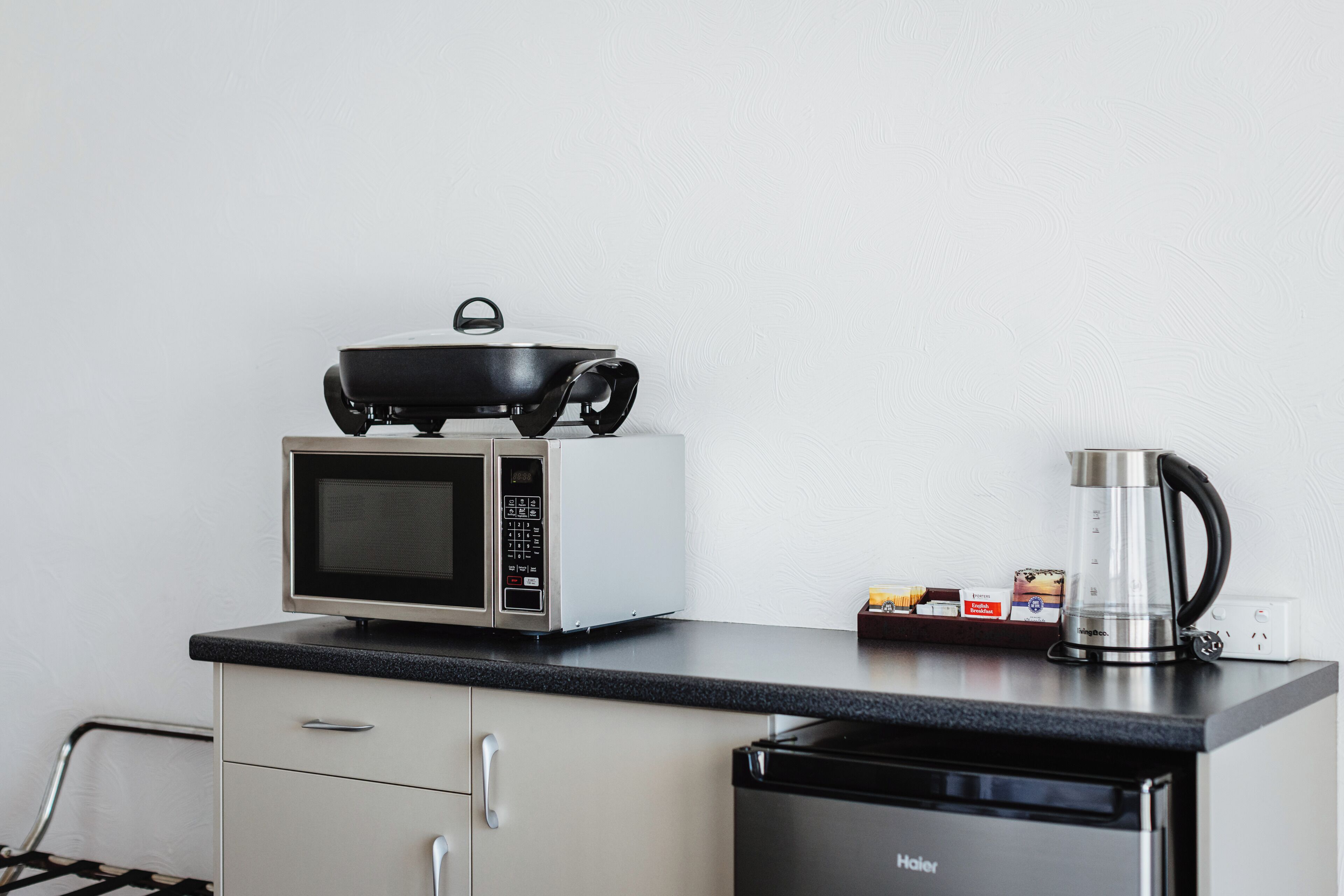 A kitchenette with a microwave, a small stove, a coffee maker, and a dishwasher.