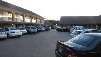 Un estacionamiento con varios autos estacionados frente a un motel de edificios de ladrillo y techo de tejas.