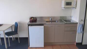 Una kitchenette compacta equipada con refrigerador, pileta y microondas.