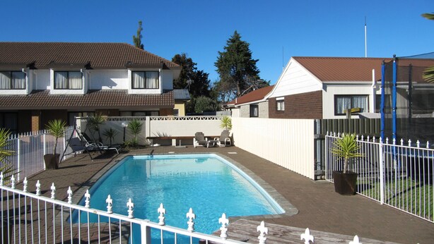 Ein Swimmingpool, umgeben von einem weißen Zaun mit verzierten Pfosten.