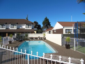 Een buitenzwembad, parasols bij het zwembad en ligstoelen