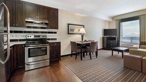 A modern kitchen with stainless steel appliances, a dining area with a table and chairs, and a large window offering a view. - Best Western Pacific Inn (Vernon)
